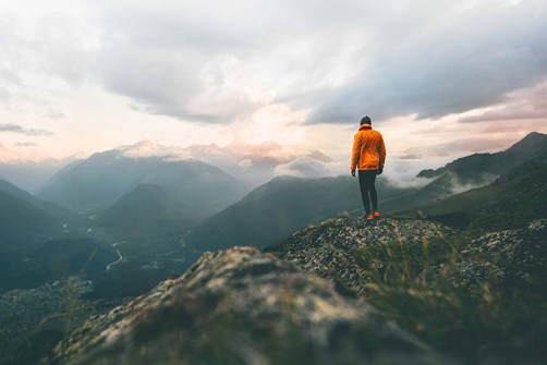 Person standing on top of a fell looking at what they have achieved 