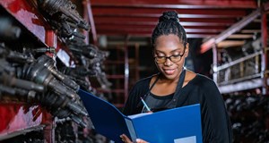 Woman holding a clipboard standing in auto parts factory