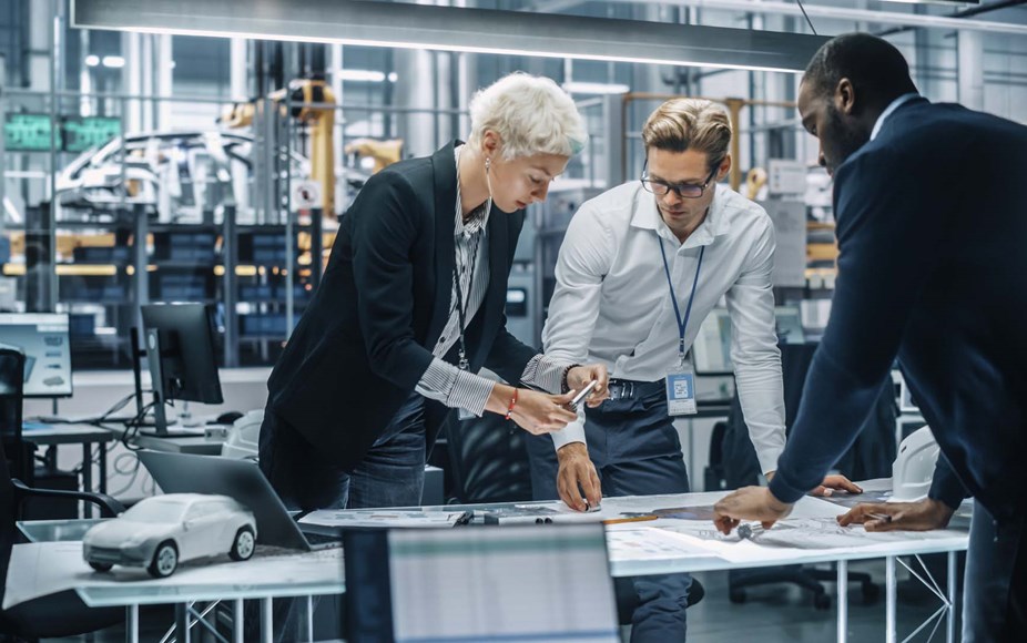 Team of automotive engineers working in office at car factory