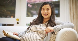 Woman who is pregnant sat down with a book in her hand