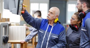 Engineer and apprentices working on machines in a factory