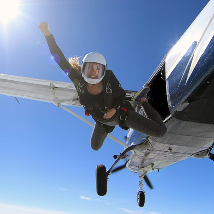 Female skydiver jumping out of a flying aeroplane in beautiful blue sky 
