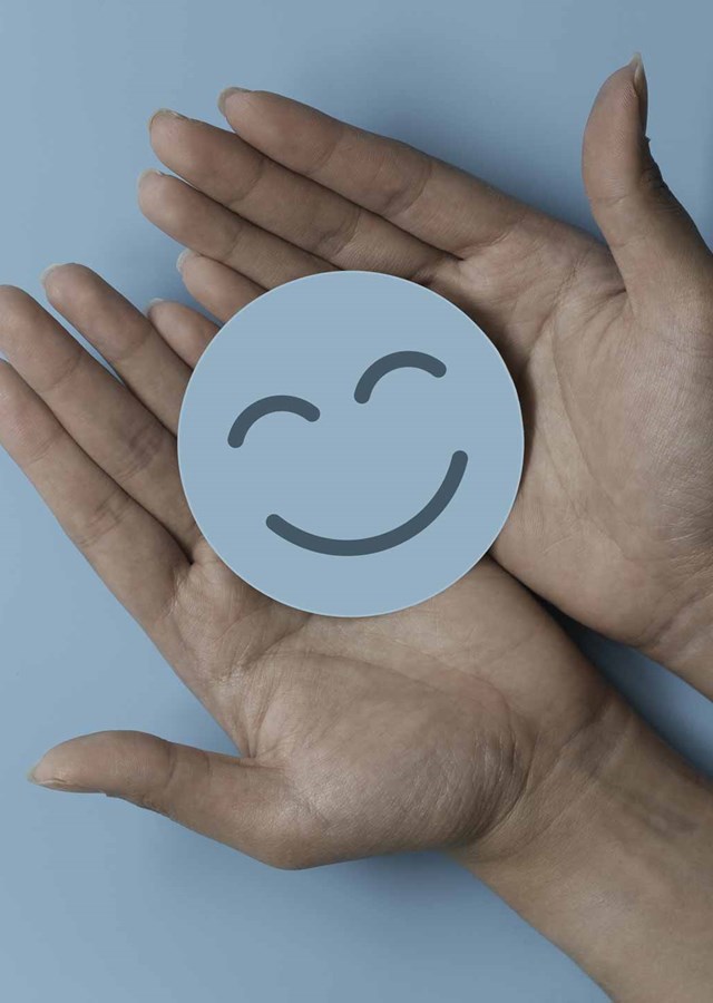 Smiling face paper circle held in two palms