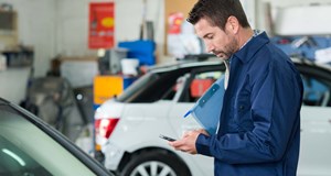 Garage technician searching for jobs on social media channels using a mobile phone