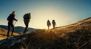 Group of four hikers, walking up a mountain in England at sunset