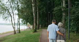 Two people walking together with their arm around each other showing support