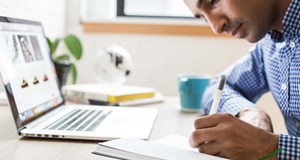 Man preparing for typical interview questions by researching information on the internet and making notes
