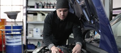 A mechanic working on a car engine by themselves