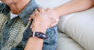 A person supporting their parent with a hand on their shoulder