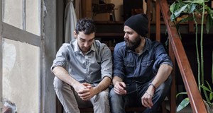 Two people sitting on a flight of stairs chatting to tackle loneliness