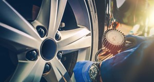 A pair of hands checking the pressure of a car tyre 