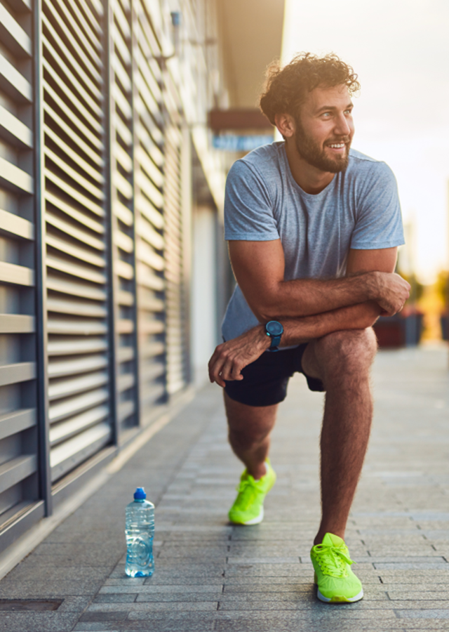 Young man exercising/stretching in an urban area. Practicing good self care to look after his health and wellbeing